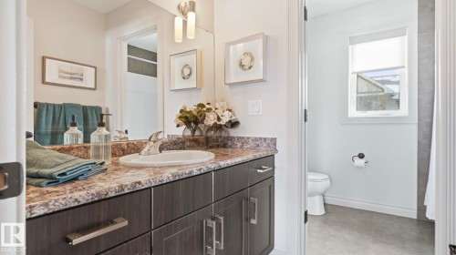 The bathroom features a vanity with a patterned countertop, a sink with a chrome faucet, and a large mirror - 131 North Ridge Drive, St. Albert, AB - Indoor Photo Showing Bathroom