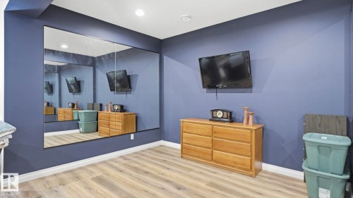 Spacious room with light wood-style flooring, a large wall-mounted mirror, and recessed lighting - 131 North Ridge Drive, St. Albert, AB - Indoor