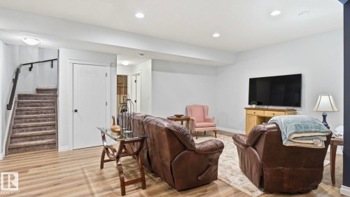 Living area with light wood-style flooring, a staircase with carpeted treads and a dark handrail, and recessed lighting - 131 North Ridge Drive, St. Albert, AB - Indoor