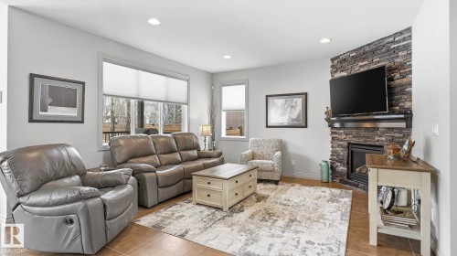 The living area features tile flooring, recessed lighting, and a corner fireplace with a stone surround - 131 North Ridge Drive, St. Albert, AB - Indoor Photo Showing Living Room With Fireplace