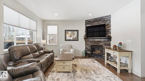 The living room features large windows, recessed lighting, and a corner stone fireplace with a mantel - 131 North Ridge Drive, St. Albert, AB - Indoor Photo Showing Living Room With Fireplace