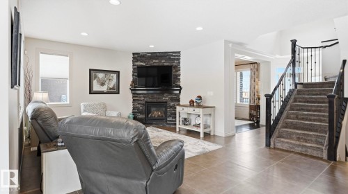 The living area features a stone-clad fireplace and recessed lighting, with a carpeted staircase visible from the main living space - 131 North Ridge Drive, St. Albert, AB - Indoor Photo Showing Living Room With Fireplace