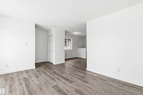 This interior space features light-toned wood-style flooring and freshly painted white walls - 16223 55A Street, Edmonton, AB - Indoor Photo Showing Other Room