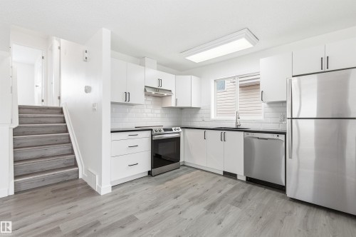 The kitchen features white cabinetry, stainless steel appliances, and a white subway tile backsplash - 16223 55A Street, Edmonton, AB - Indoor Photo Showing Kitchen With Upgraded Kitchen