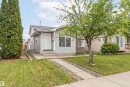 The property features a well-maintained lawn with mature trees and a paved walkway leading to the front entrance - 16223 55A Street, Edmonton, AB  - Outdoor With Facade 