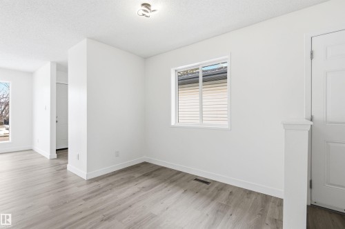 This interior space features light-colored flooring, a window providing natural light, and a white door with paneling - 16223 55A Street, Edmonton, AB - Indoor Photo Showing Other Room