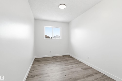 This room features light-colored laminate flooring, white walls, and a window providing natural light - 16223 55A Street, Edmonton, AB - Indoor Photo Showing Other Room