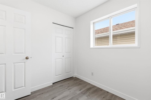 This room features light-colored walls, gray wood-look flooring, and a window with white trim - 16223 55A Street, Edmonton, AB - Indoor Photo Showing Other Room