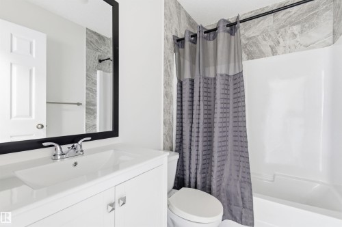The bathroom features a white vanity with a rectangular sink, chrome faucet, and a large mirror with a black frame - 16223 55A Street, Edmonton, AB - Indoor Photo Showing Bathroom