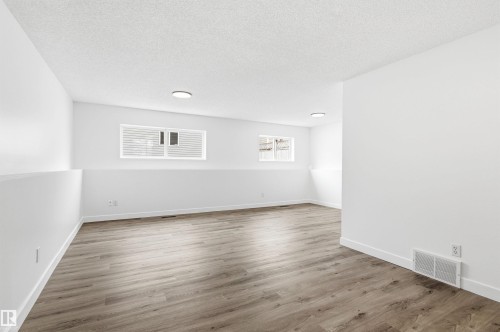 This spacious room features light-toned flooring, white walls, and two windows allowing for natural illumination - 16223 55A Street, Edmonton, AB - Indoor Photo Showing Other Room