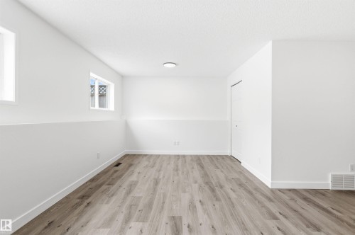 This room features light wood-style flooring, white walls, and two windows allowing for natural light - 16223 55A Street, Edmonton, AB - Indoor Photo Showing Other Room
