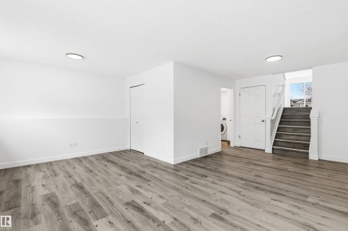 Spacious area featuring wood-look flooring, white walls, and bright overhead lighting - 16223 55A Street, Edmonton, AB - Indoor Photo Showing Other Room