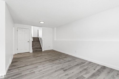 This expansive room features white walls, a white ceiling, and light-toned wood-style flooring, offering a versatile space - 16223 55A Street, Edmonton, AB - Indoor Photo Showing Other Room