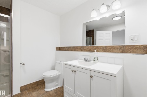 The bathroom features a white vanity with a rectangular sink, a toilet, and a stand-up shower with a glass door - 16223 55A Street, Edmonton, AB - Indoor Photo Showing Bathroom