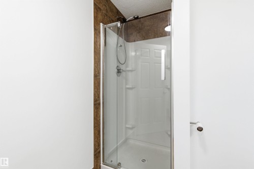 The shower features a clear glass enclosure, a white shower base, and brown tiled walls - 16223 55A Street, Edmonton, AB - Indoor Photo Showing Bathroom