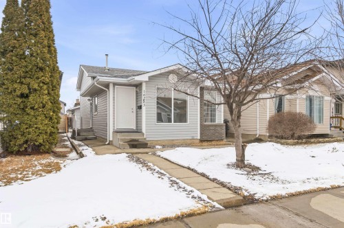 This property features a light grey exterior siding, a welcoming front door, and a concrete pathway leading to the entrance - 16223 55A Street, Edmonton, AB - Outdoor With Facade