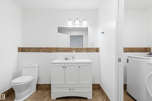 The bathroom features a white vanity with a rectangular sink, a toilet, and brown floor tiling - 16223 55A Street, Edmonton, AB - Indoor Photo Showing Other Room