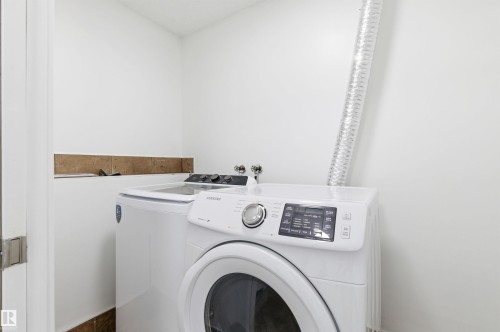 Laundry area featuring white walls, a front-load washing machine, and a top-load washing machine - 16223 55A Street, Edmonton, AB - Indoor Photo Showing Laundry Room