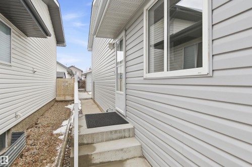 The property features light-colored horizontal siding, a concrete staircase, and a white framed window - 16223 55A Street, Edmonton, AB - Outdoor With Exterior