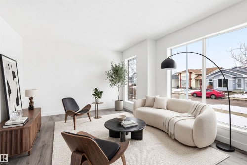 This living space features light wood-style flooring, white walls, and a large window providing natural light - 16223 55A Street, Edmonton, AB - Indoor Photo Showing Living Room