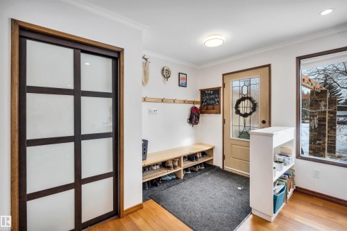 The property features a welcoming entryway with hardwood flooring, a window offering natural light, and a stylish front door with decorative glass inserts - 4208 89 Street Nw, Edmonton, AB - Indoor Photo Showing Other Room