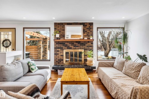 The living area features hardwood floors, a brick fireplace with a mantel, and recessed lighting - 4208 89 Street Nw, Edmonton, AB - Indoor Photo Showing Living Room With Fireplace