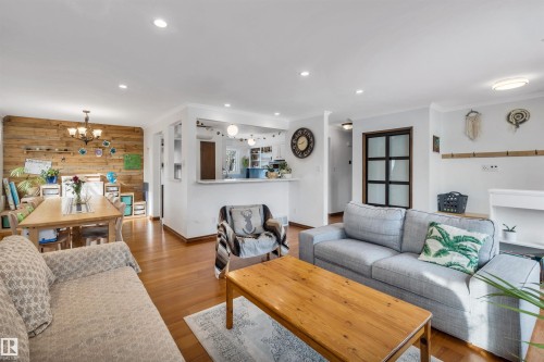 Open concept living and dining area featuring hardwood floors, recessed lighting, and a dining area with a wood accent wall - 4208 89 Street Nw, Edmonton, AB - Indoor Photo Showing Living Room
