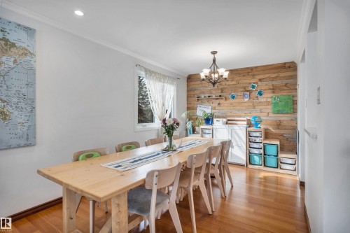 This room features rich hardwood flooring and a prominent accent wall crafted from natural wood planks - 4208 89 Street Nw, Edmonton, AB - Indoor Photo Showing Dining Room