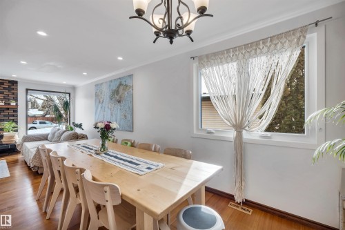 Dining area with hardwood floors, a large window providing natural light, and a chandelier - 4208 89 Street Nw, Edmonton, AB - Indoor Photo Showing Dining Room