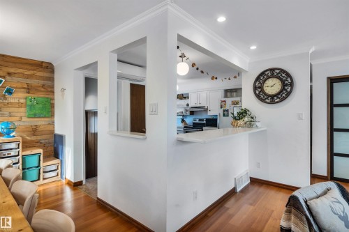This living area features rich hardwood flooring, crown molding, and recessed lighting - 4208 89 Street Nw, Edmonton, AB - Indoor