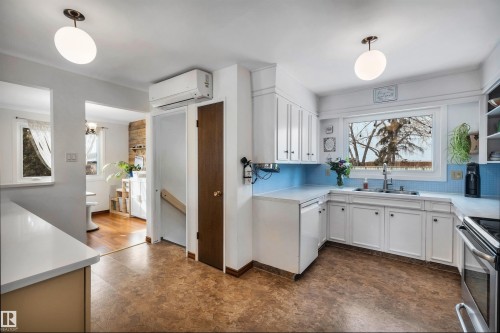 The kitchen features white cabinetry, blue tiled backsplash, and a window above the sink - 4208 89 Street Nw, Edmonton, AB - Indoor Photo Showing Kitchen With Double Sink