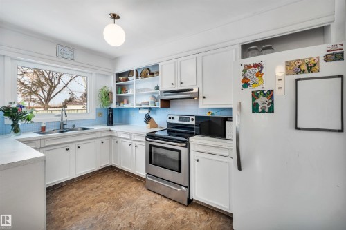 The kitchen features white cabinetry, light countertops, and a light blue tiled backsplash - 4208 89 Street Nw, Edmonton, AB - Indoor Photo Showing Kitchen With Double Sink