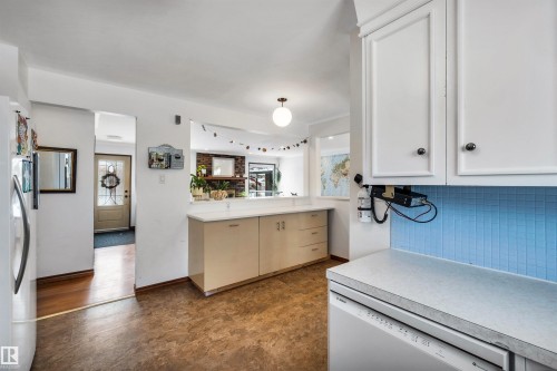 The kitchen features white cabinetry, a light blue tile backsplash, a built-in dishwasher, and a light-colored countertop - 4208 89 Street Nw, Edmonton, AB - Indoor Photo Showing Kitchen