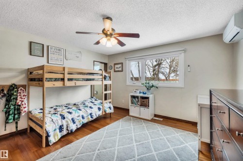 A bright room featuring wood flooring, a window with views of trees, and a ceiling fan - 4208 89 Street Nw, Edmonton, AB - Indoor Photo Showing Bedroom