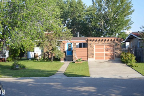 The property features a brick exterior, an integrated garage with a light-toned door, and a vibrant blue front door - 4208 89 Street Nw, Edmonton, AB - Outdoor
