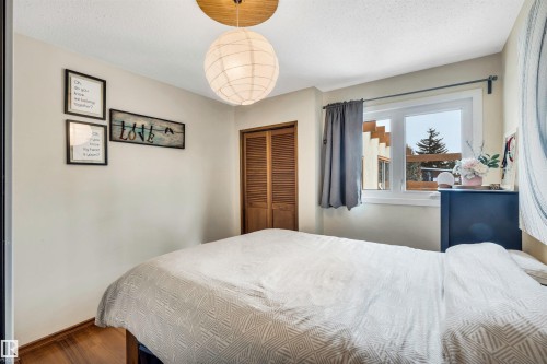 Room with hardwood flooring, a window offering views of the exterior, and a wooden bi-fold closet door - 4208 89 Street Nw, Edmonton, AB - Indoor Photo Showing Bedroom