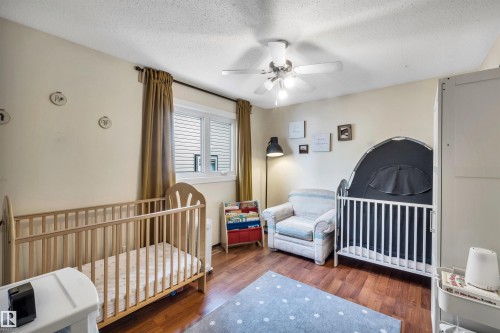 This room features hardwood floors, a window with blinds and drapes, and a ceiling fan with integrated lighting - 4208 89 Street Nw, Edmonton, AB - Indoor Photo Showing Bedroom