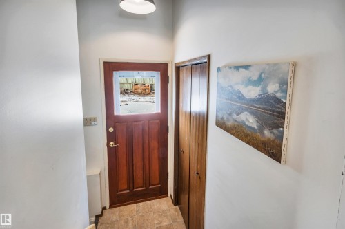 This entry area features a paneled wooden door with a window and a neutral-toned tiled floor - 4208 89 Street Nw, Edmonton, AB - Indoor Photo Showing Other Room