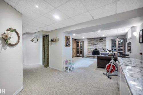 The property features a spacious room with carpeted flooring and recessed lighting - 4208 89 Street Nw, Edmonton, AB - Indoor