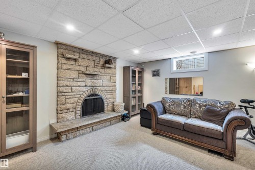 Living area featuring a stone fireplace with hearth, recessed lighting, and carpeted floors - 4208 89 Street Nw, Edmonton, AB - Indoor Photo Showing Basement With Fireplace