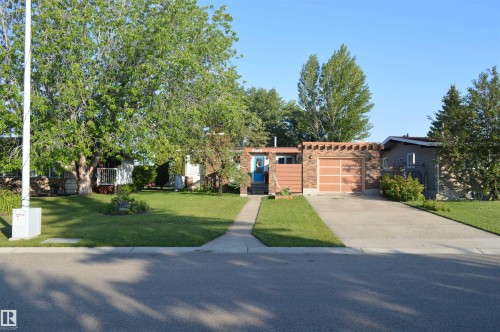 The property features an extensive front lawn with mature trees and a paved driveway leading to an attached garage - 4208 89 Street Nw, Edmonton, AB - Outdoor