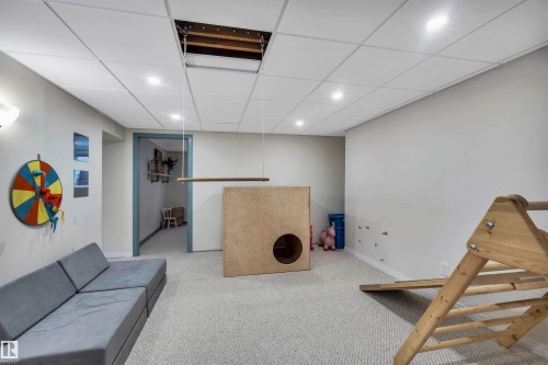The property features a spacious room with light-colored carpeting, a drop ceiling with recessed lighting, and light-colored walls - 4208 89 Street Nw, Edmonton, AB - Indoor Photo Showing Basement