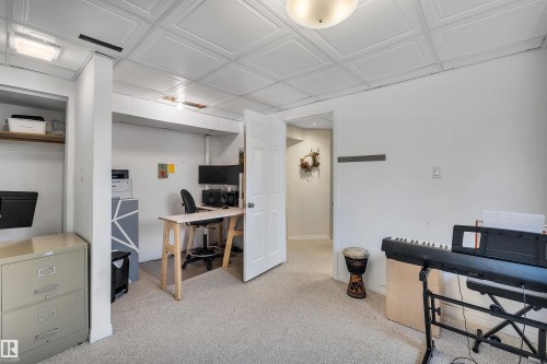 The property features a versatile room with carpeted flooring, white walls, and a white ceiling with a textured tile pattern - 4208 89 Street Nw, Edmonton, AB - Indoor