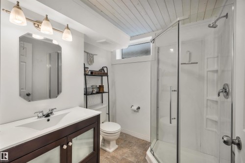 Bathroom featuring a dark wood vanity with a white countertop and rectangular sink, a shower with a clear glass enclosure, and a toilet - 4208 89 Street Nw, Edmonton, AB - Indoor Photo Showing Bathroom