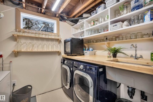 The property features a dedicated laundry area with a window, a wooden countertop with an integrated sink, and open shelving for storage - 4208 89 Street Nw, Edmonton, AB - Indoor Photo Showing Laundry Room
