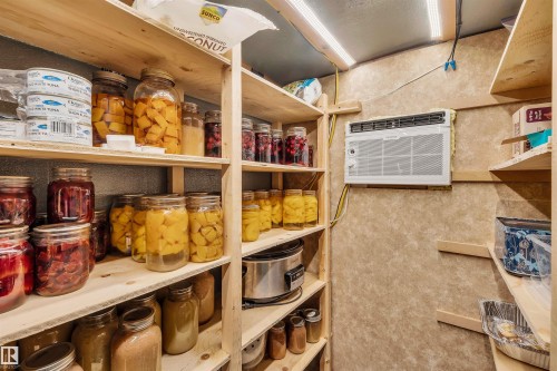 The property features a dedicated storage area with extensive wooden shelving and an installed air conditioning unit - 4208 89 Street Nw, Edmonton, AB - Indoor Photo Showing Other Room