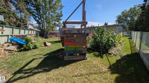 The property features a fenced yard with a lawn, mature trees, and garden beds - 4208 89 Street Nw, Edmonton, AB - Outdoor