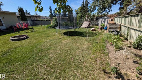 The property features an expansive backyard with a well-maintained lawn and a dedicated garden area - 4208 89 Street Nw, Edmonton, AB - Outdoor With Backyard
