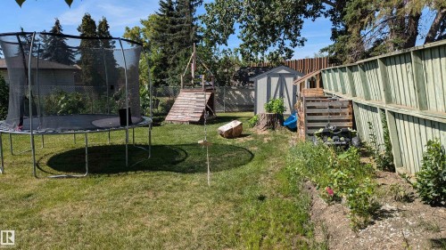 The property includes a spacious grassy yard with mature trees, a garden shed, and a wooden fence along the perimeter - 4208 89 Street Nw, Edmonton, AB - Outdoor