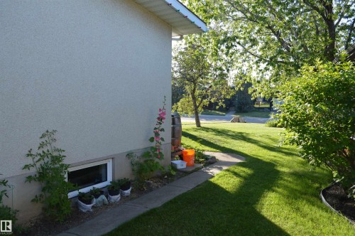 The property features a well-maintained lawn and mature trees, alongside a concrete pathway - 4208 89 Street Nw, Edmonton, AB - Outdoor